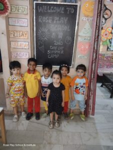 Group of happy preschool children standing in front of a summer camp welcome board at Rose Play School